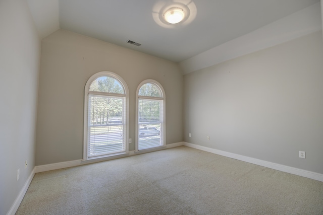 carpeted spare room with vaulted ceiling