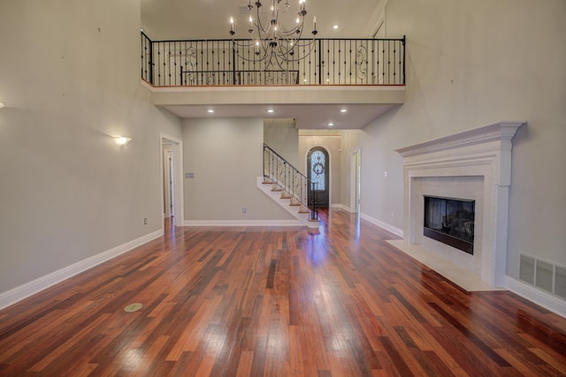 unfurnished living room with a fireplace, dark wood-type flooring, and a high ceiling