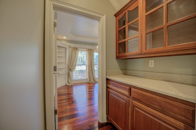 bar featuring light stone counters, dark hardwood / wood-style flooring, and ornamental molding