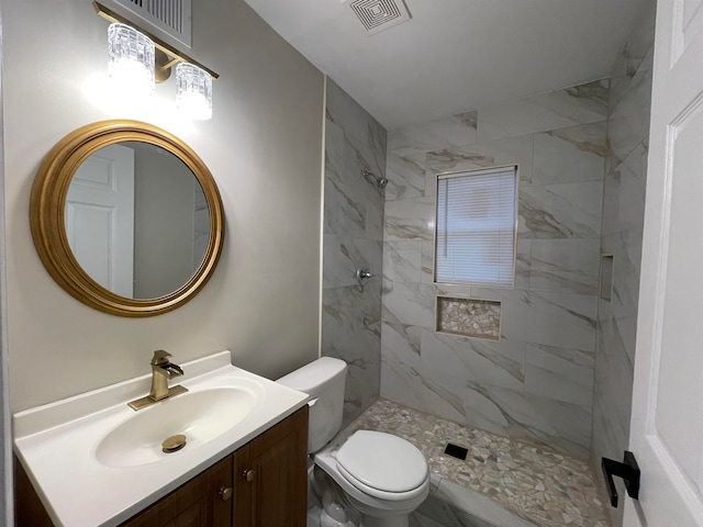 bathroom featuring tiled shower, vanity, and toilet