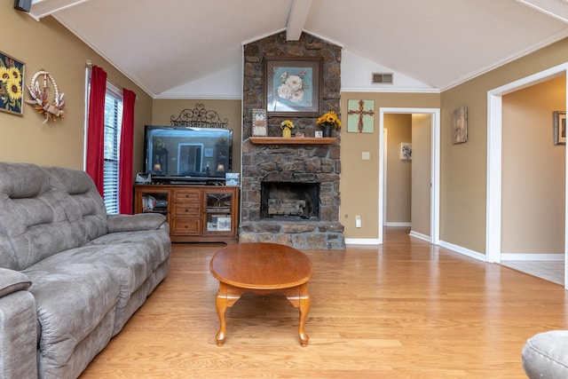 living room featuring vaulted ceiling with beams, crown molding, a stone fireplace, and light wood-type flooring