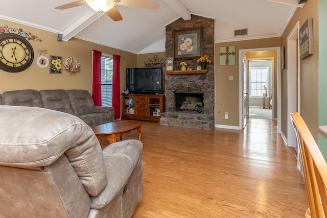 living room with ceiling fan, vaulted ceiling with beams, crown molding, light hardwood / wood-style floors, and a fireplace