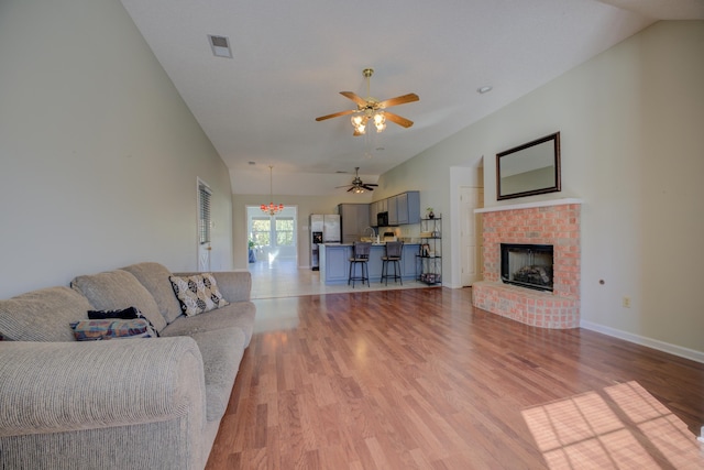 living room featuring a fireplace, light hardwood / wood-style floors, ceiling fan, and lofted ceiling