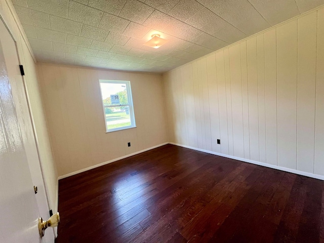 empty room with wood walls and dark hardwood / wood-style flooring