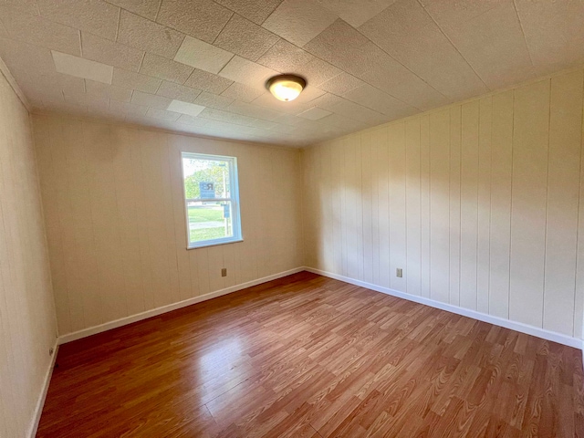 spare room featuring hardwood / wood-style floors and wooden walls