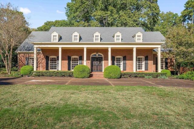 cape cod home with covered porch and a front yard