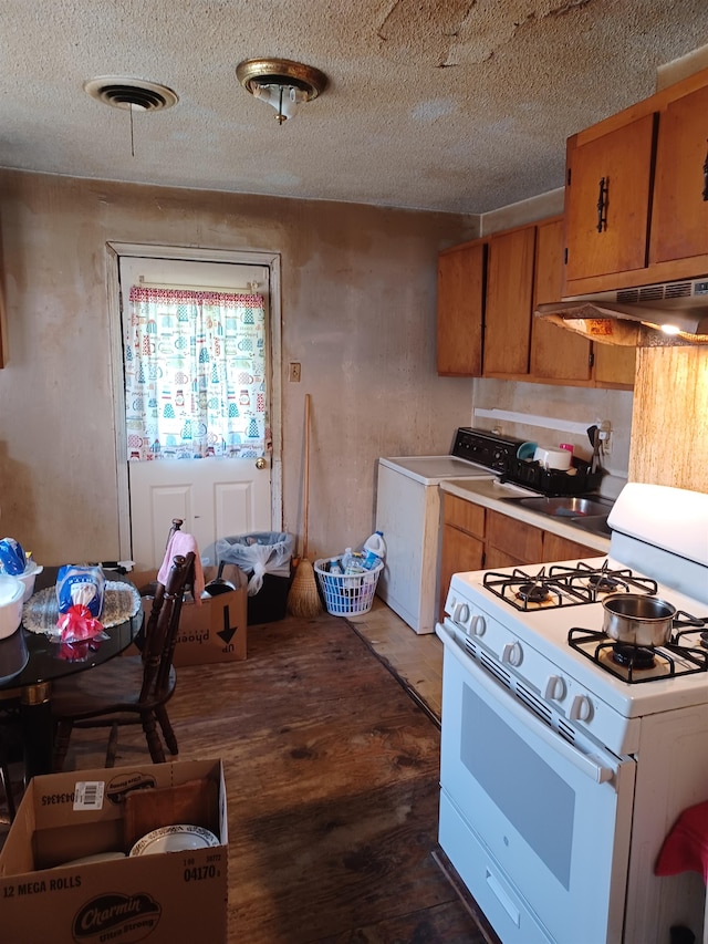 kitchen with dark hardwood / wood-style floors, washer / dryer, white gas range, and a textured ceiling