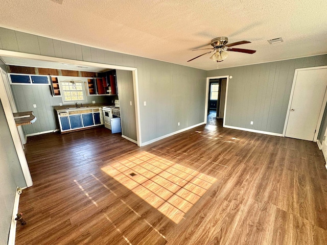 unfurnished living room featuring hardwood / wood-style floors, ceiling fan, sink, and a textured ceiling