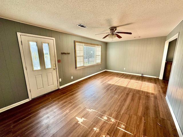 foyer entrance featuring ceiling fan, wood walls, and dark hardwood / wood-style flooring