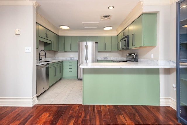 kitchen with hardwood / wood-style floors, green cabinetry, and appliances with stainless steel finishes