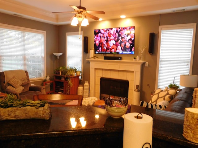 living room with ornamental molding, a tile fireplace, and ceiling fan