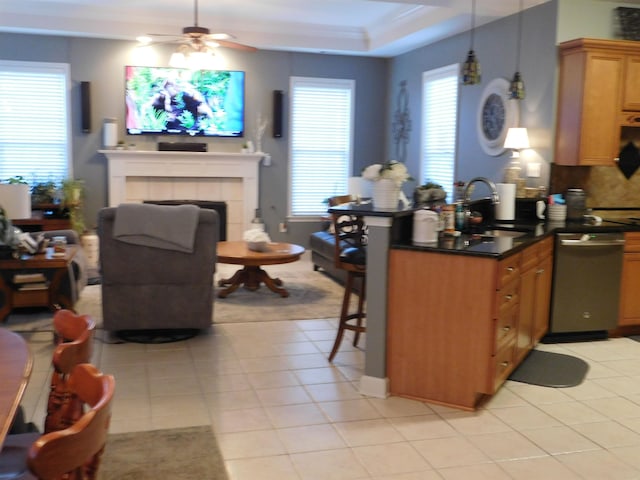 kitchen with sink, a breakfast bar, a tiled fireplace, decorative light fixtures, and stainless steel dishwasher