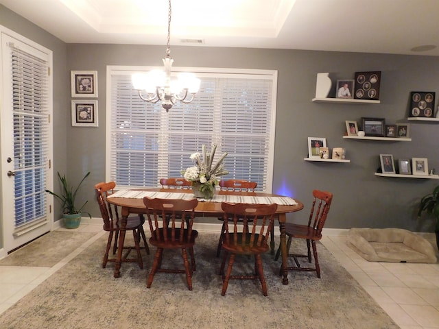 tiled dining area with an inviting chandelier and a tray ceiling