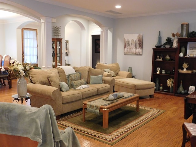 living room featuring crown molding, light hardwood / wood-style floors, and decorative columns