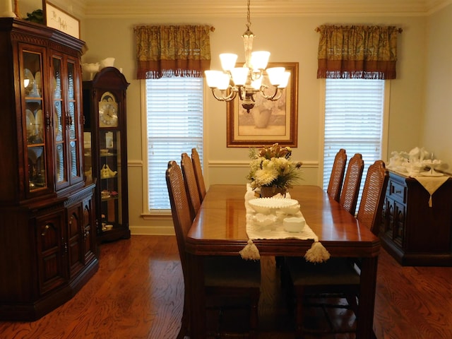 dining room with an inviting chandelier, crown molding, and dark wood-type flooring