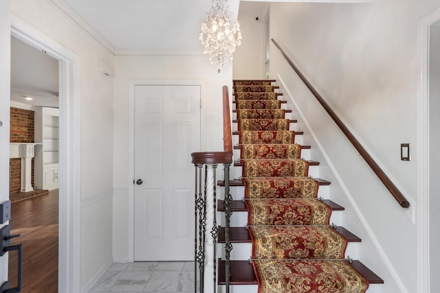 stairs with crown molding and an inviting chandelier