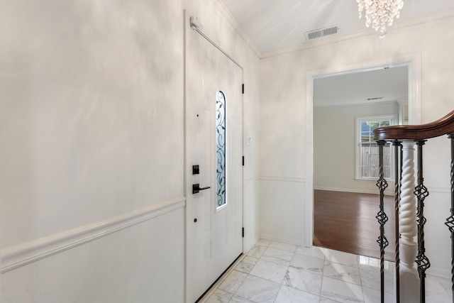 entrance foyer with light wood-type flooring, crown molding, and a chandelier