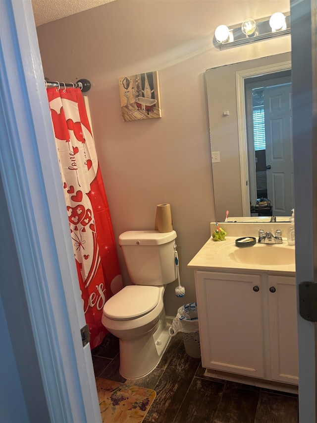 bathroom with hardwood / wood-style floors, vanity, toilet, and a textured ceiling