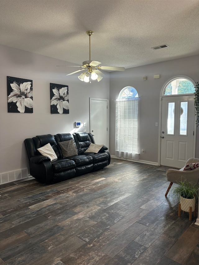 living room with a textured ceiling, dark hardwood / wood-style flooring, and ceiling fan