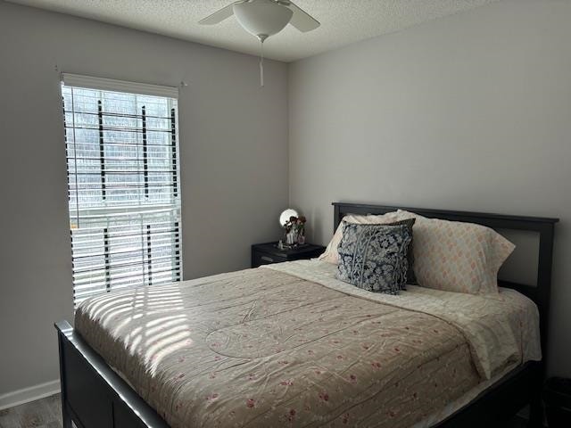 bedroom featuring ceiling fan, hardwood / wood-style floors, and a textured ceiling