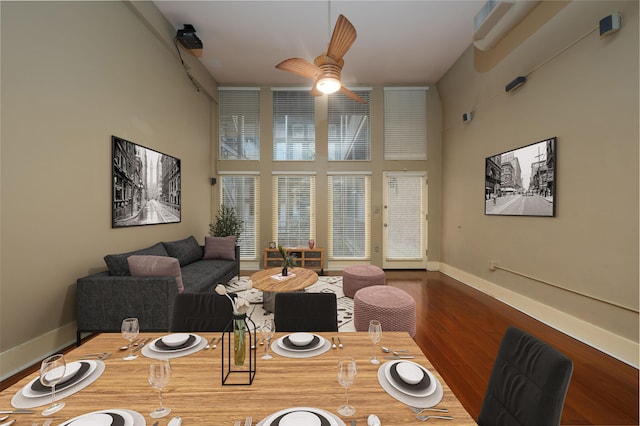 dining room with ceiling fan, a towering ceiling, and wood-type flooring