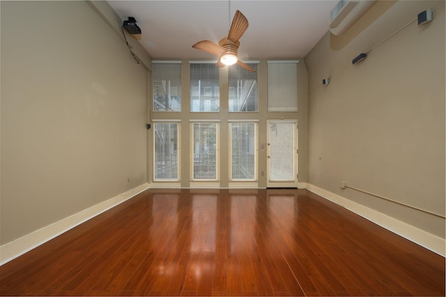 spare room with a towering ceiling, wood-type flooring, and ceiling fan