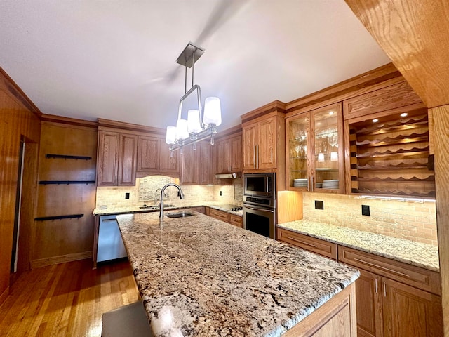 kitchen with a kitchen island with sink, sink, hanging light fixtures, dark hardwood / wood-style floors, and stainless steel appliances