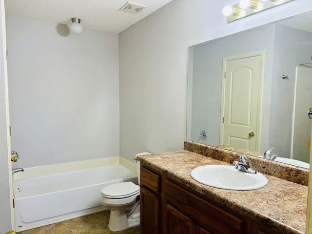 bathroom with tile patterned floors, a textured ceiling, toilet, a bathtub, and vanity