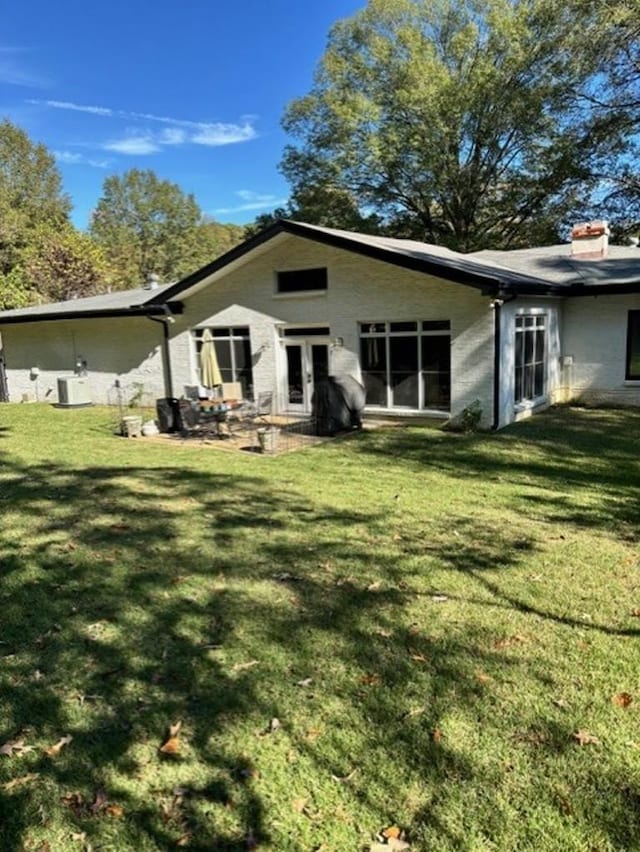 rear view of property featuring a patio and a lawn