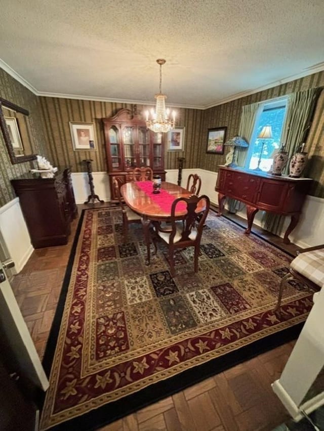 dining room featuring a textured ceiling, dark parquet floors, an inviting chandelier, and ornamental molding