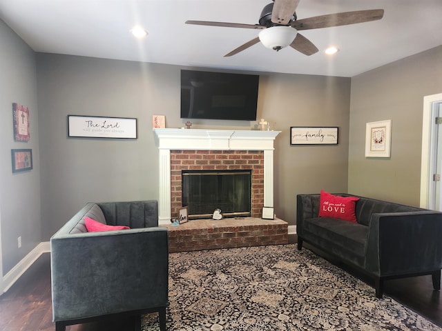 living room featuring hardwood / wood-style floors, ceiling fan, and a brick fireplace