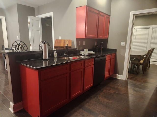 kitchen featuring dishwasher, dark wood-type flooring, sink, dark stone countertops, and kitchen peninsula