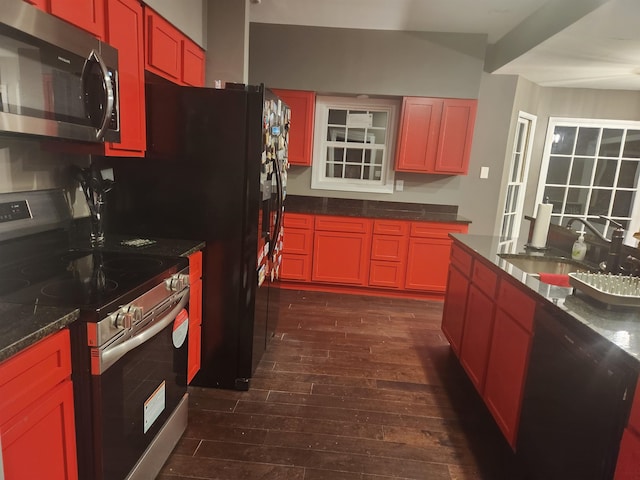 kitchen with dark stone countertops, sink, dark hardwood / wood-style floors, and appliances with stainless steel finishes