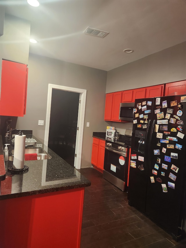 kitchen with kitchen peninsula, stainless steel appliances, dark stone counters, and dark wood-type flooring