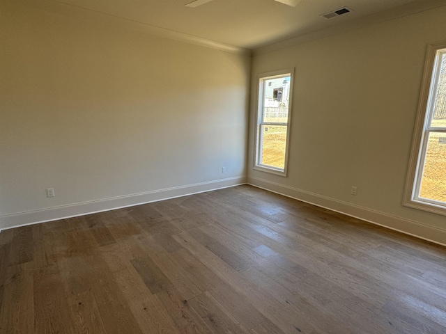 unfurnished room featuring ornamental molding, visible vents, dark wood finished floors, and baseboards