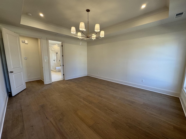 spare room with baseboards, visible vents, a raised ceiling, dark wood-type flooring, and a chandelier