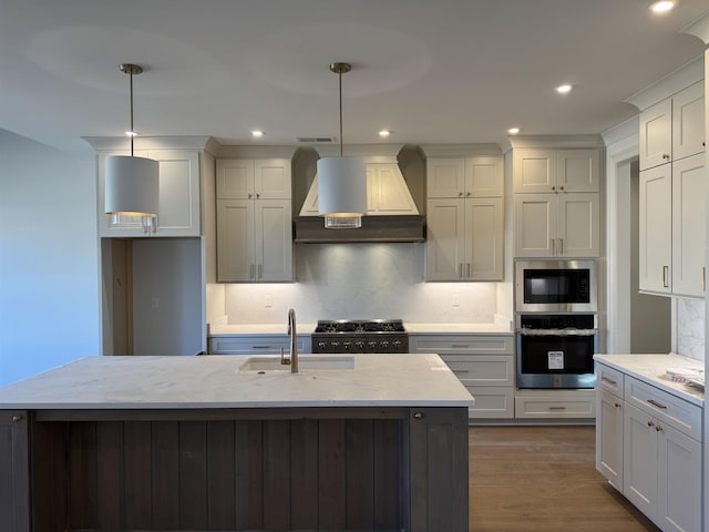 kitchen featuring light stone counters, dark wood finished floors, appliances with stainless steel finishes, a sink, and wall chimney range hood