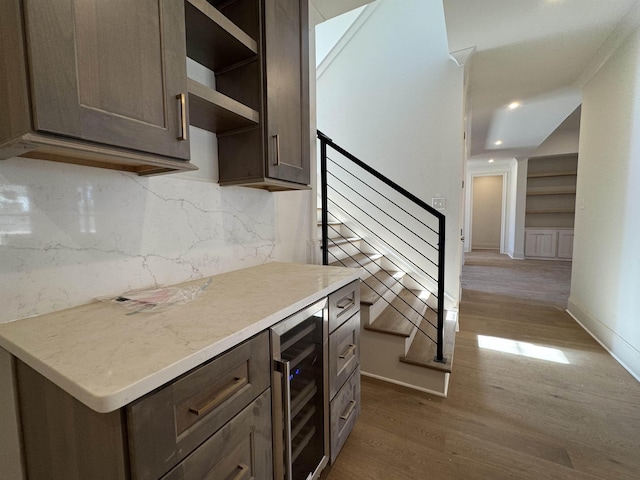 kitchen with tasteful backsplash, light countertops, dark brown cabinets, wood finished floors, and beverage cooler