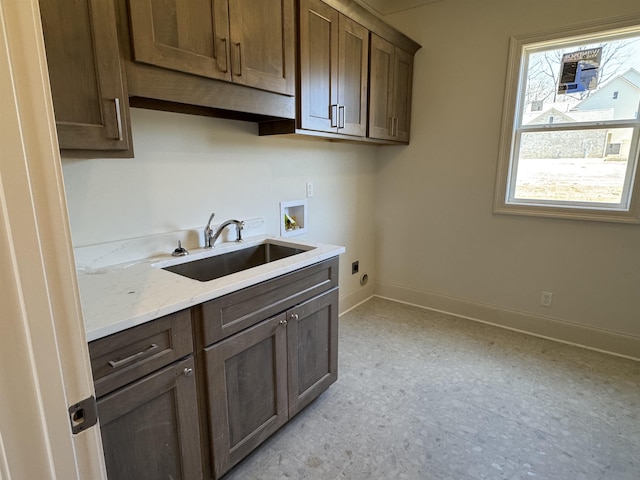 kitchen featuring a sink, light stone countertops, and baseboards