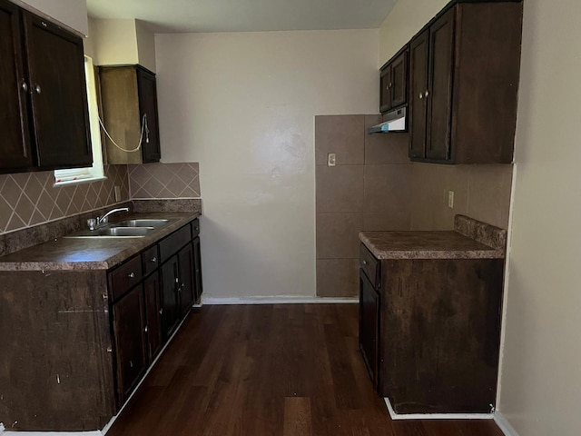 kitchen featuring backsplash, dark brown cabinets, sink, and dark wood-type flooring