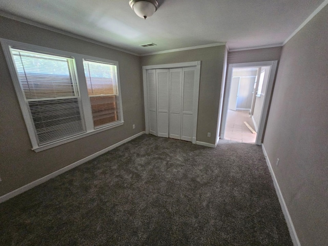 unfurnished bedroom with a closet, dark carpet, and ornamental molding