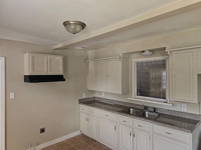 kitchen featuring dark tile patterned floors, white cabinetry, and sink