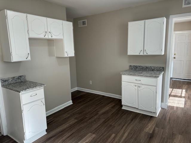 kitchen with white cabinets, dark hardwood / wood-style floors, and light stone counters