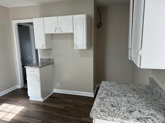 kitchen with white cabinetry, dark hardwood / wood-style flooring, and light stone countertops