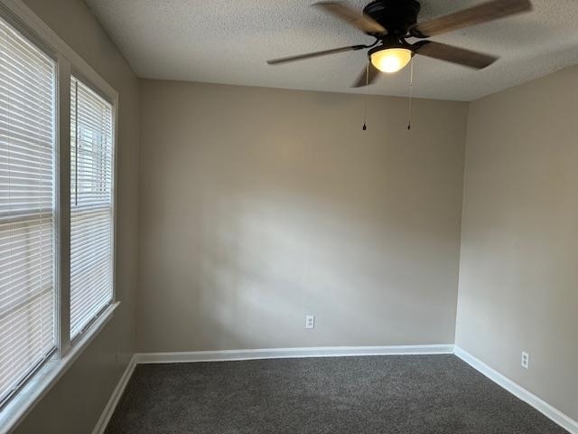 carpeted empty room with ceiling fan and a textured ceiling