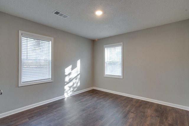 spare room featuring dark hardwood / wood-style flooring and a textured ceiling