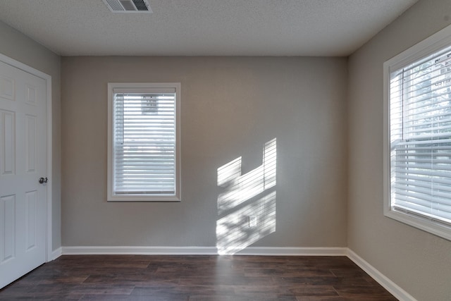 unfurnished room with dark hardwood / wood-style floors, a healthy amount of sunlight, and a textured ceiling