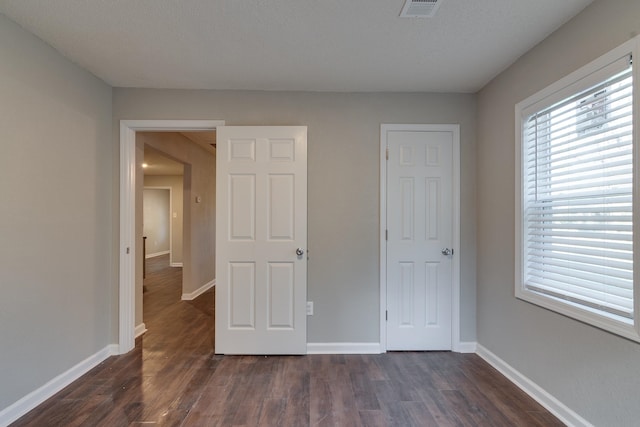 unfurnished bedroom featuring dark wood-type flooring and a textured ceiling