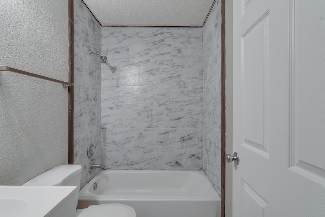 full bathroom with tiled shower / bath, vanity, a textured ceiling, and toilet