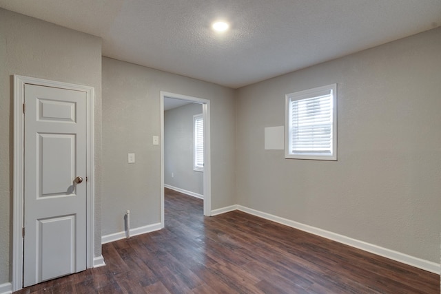 spare room with a textured ceiling and dark hardwood / wood-style floors